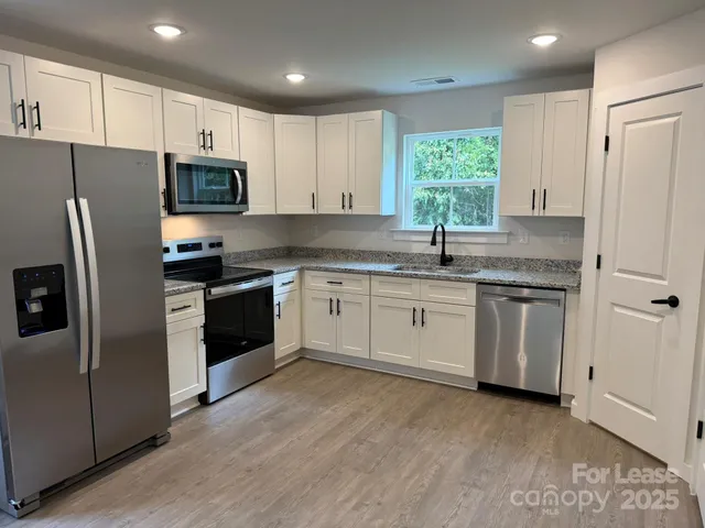 a kitchen with white cabinets stainless steel appliances and window