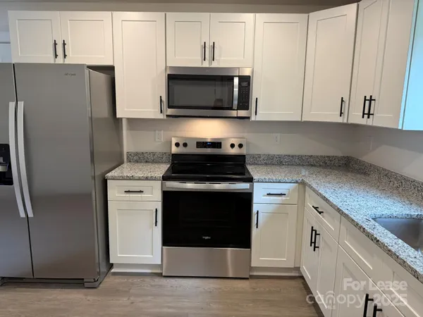 a kitchen with stainless steel appliances granite countertop a refrigerator stove and microwave