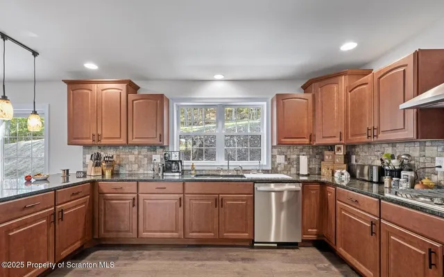 a kitchen with stainless steel appliances granite countertop a refrigerator a sink dishwasher and wooden cabinets with a granite countertops