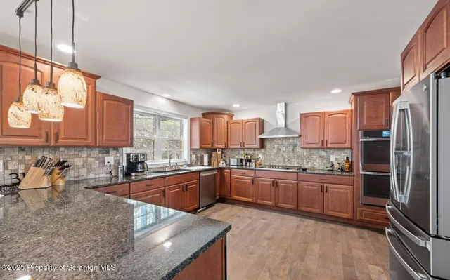 a view of a kitchen with stainless steel appliances granite countertop a refrigerator a oven and a wooden floors