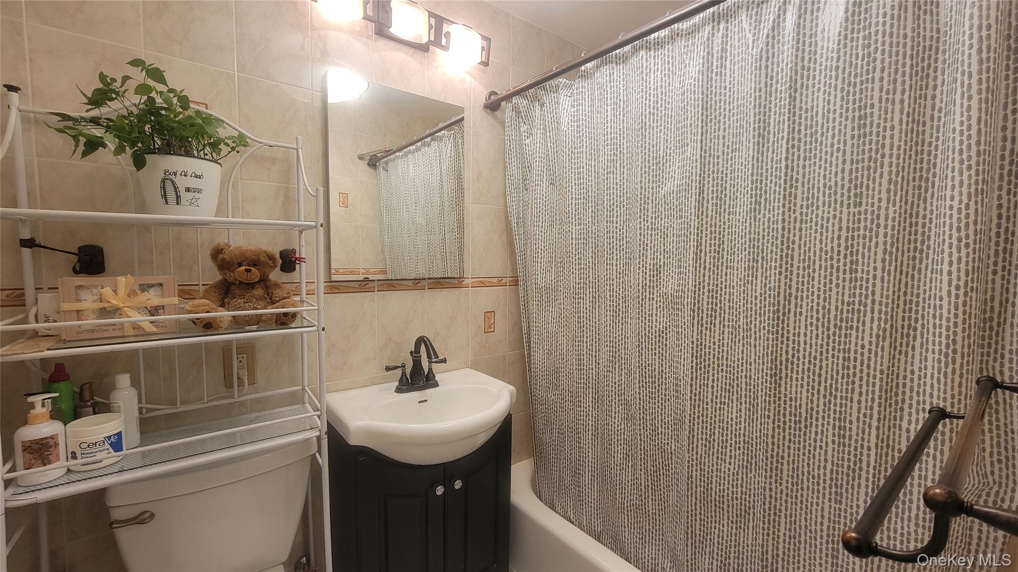 99-30 59th Avenue, Unit 5A Queens, NY 11368 - Photo 3 of 15 a bathroom with a sink a toilet and shower curtain