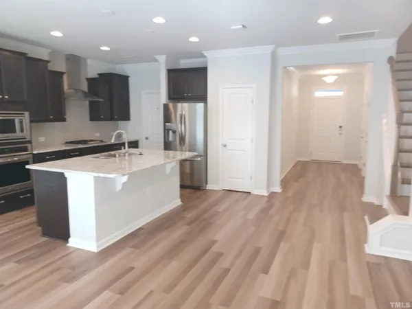 a large kitchen with stainless steel appliances granite countertop a large counter top a sink dishwasher a stove and a refrigerator with wooden floor