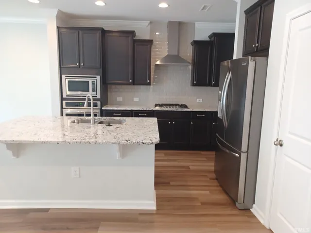 a kitchen with stainless steel appliances granite countertop a refrigerator a stove a sink and a microwave