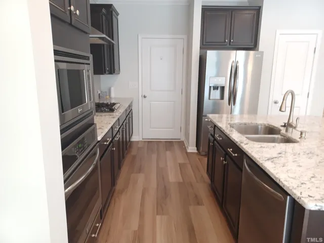 a kitchen with kitchen island granite countertop a sink stove and refrigerator