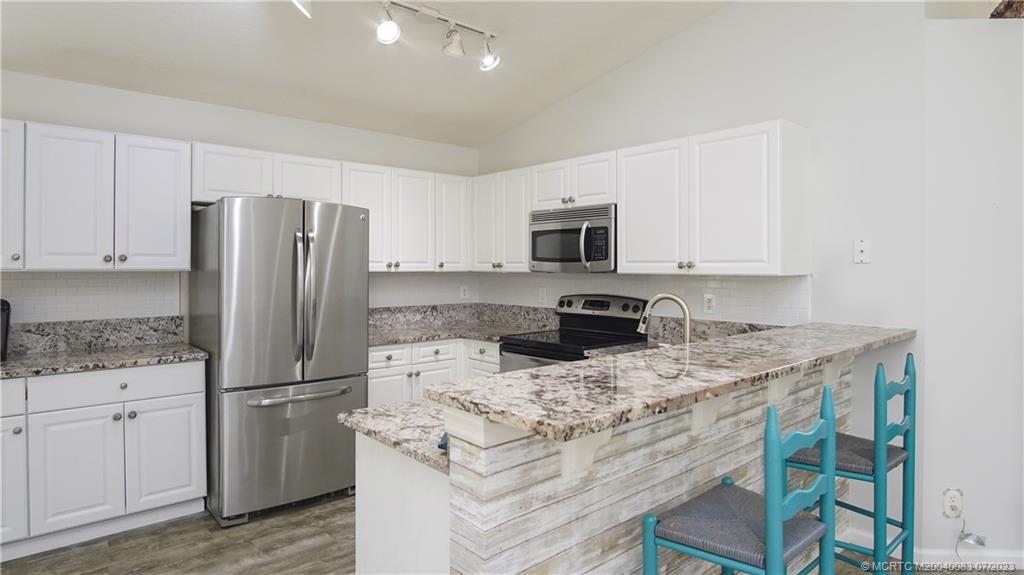 2440 Southwest Riviera Road Stuart, FL 34997 - Photo 4 of 18 a kitchen with kitchen island granite countertop appliances a sink cabinets and a counter space