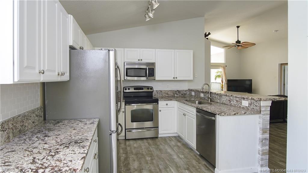 2440 Southwest Riviera Road Stuart, FL 34997 - Photo 5 of 18 a kitchen with kitchen island granite countertop a sink stove and refrigerator