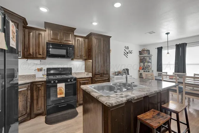 a kitchen with stainless steel appliances granite countertop a stove top oven a sink dishwasher a dining table and chairs