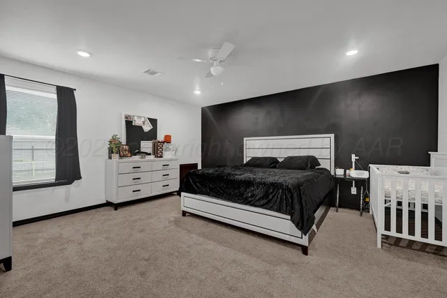 a spacious bedroom with a bed window and flat screen tv