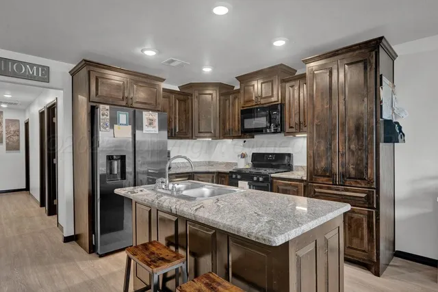 a kitchen with stainless steel appliances granite countertop a refrigerator a stove and a sink