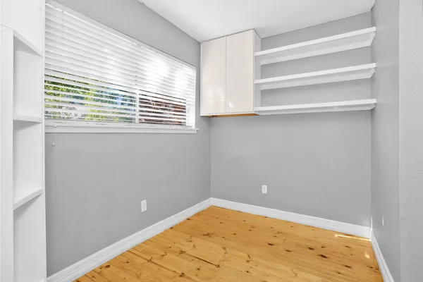 a view of empty room with wooden floor and fan