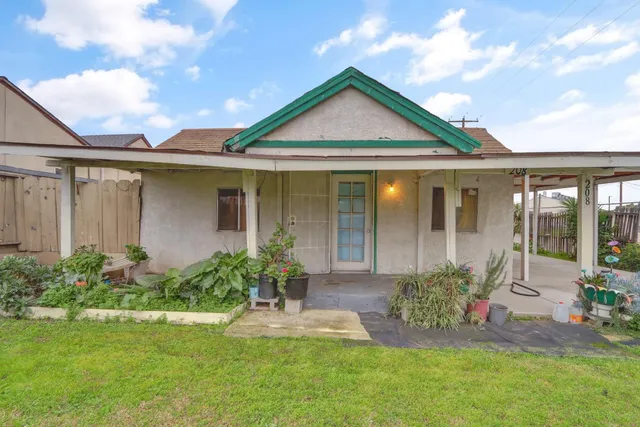 a front view of a house with a yard and potted plants