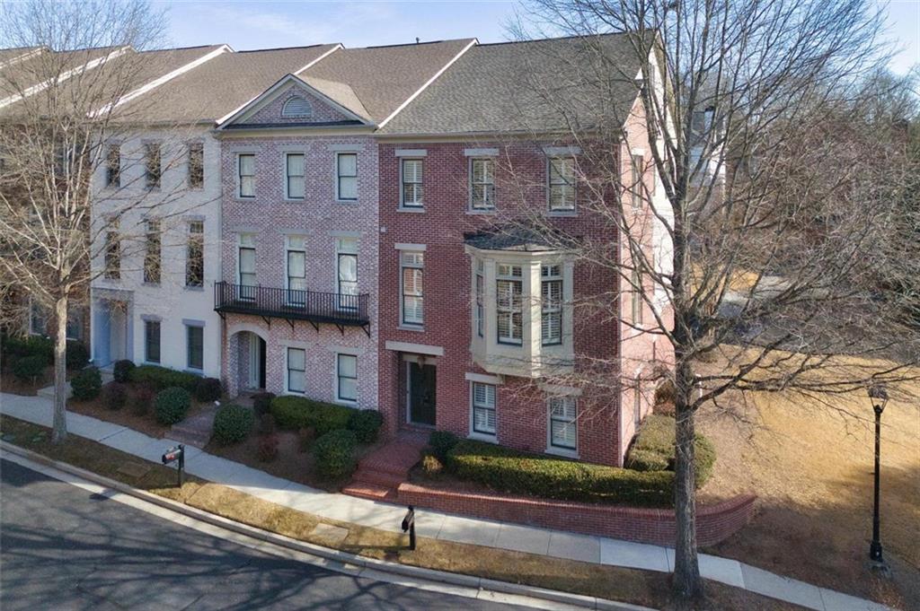 a view of a brick house with a yard and large tree