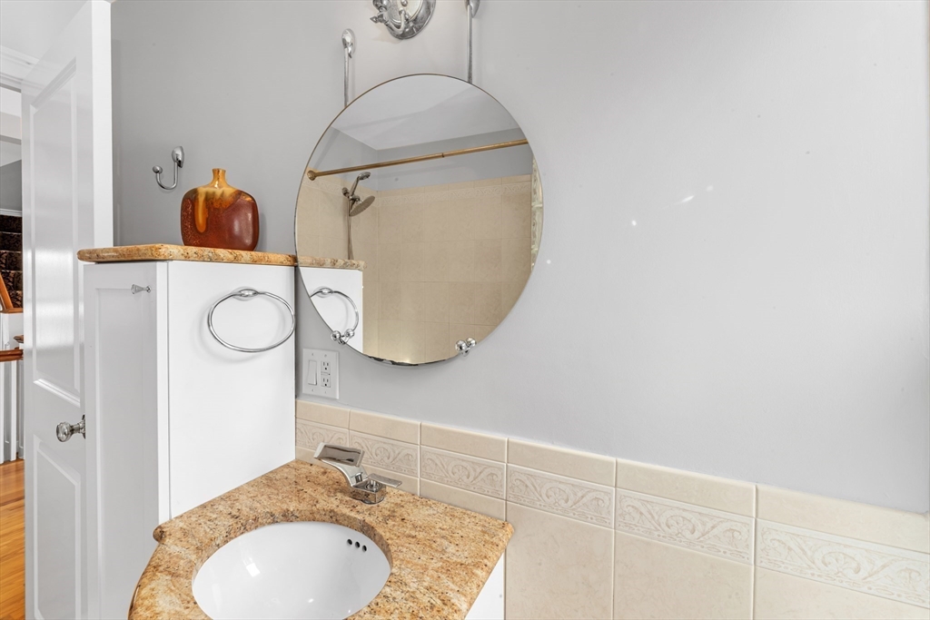 231 Lagrange Street Boston, MA 02132 - Photo 23 of 42 a bathroom with a granite countertop sink a mirror and vanity
