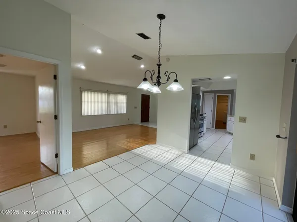 a view of a hallway with wooden floor and a chandelier