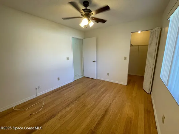 a view of a room with wooden floor and a ceiling fan