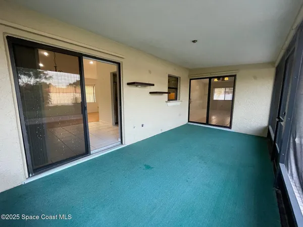 a view of empty room with floor to ceiling window and kitchen view