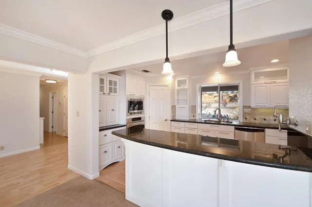 a kitchen with granite countertop white cabinets and a window