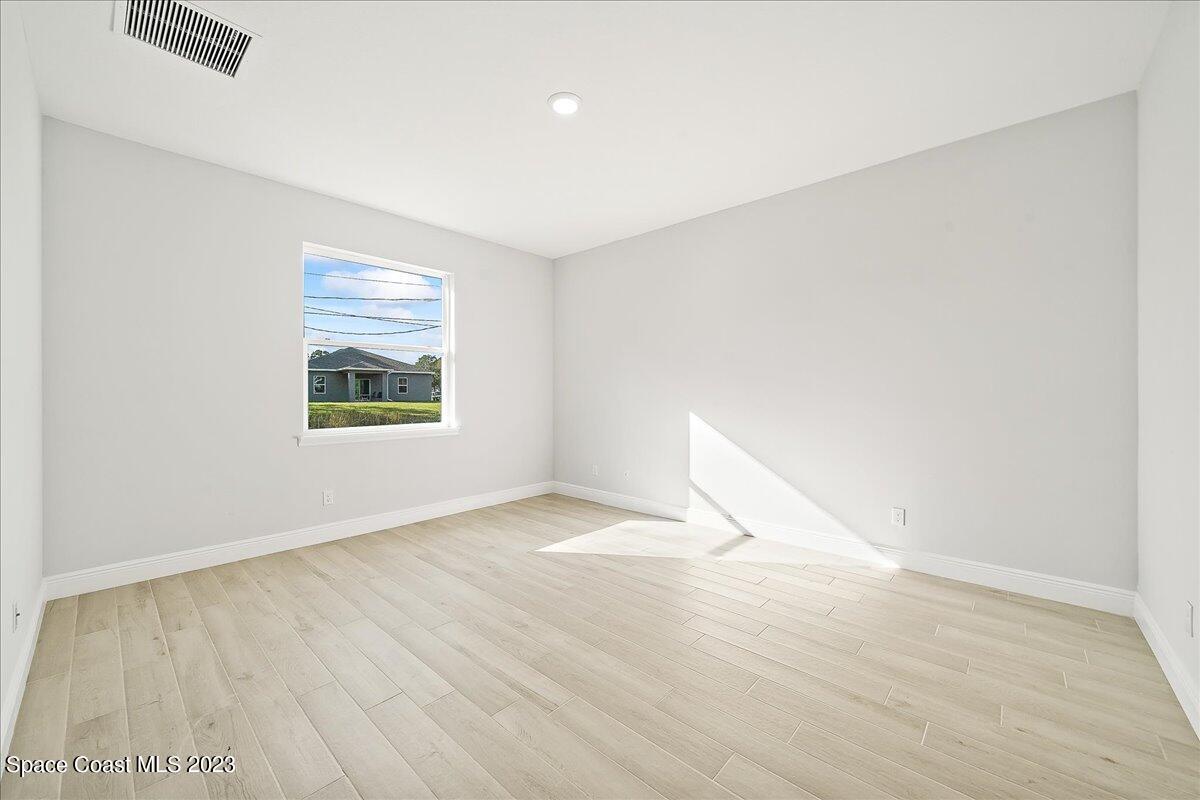 560 Topeka Road Southwest Palm Bay, FL 32908 - Photo 24 of 26 an empty room with wooden floor and windows