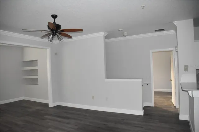 a view of empty room with wooden floor and fan