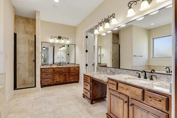 a spacious bathroom with a granite countertop double vanity sink a mirror and a shower