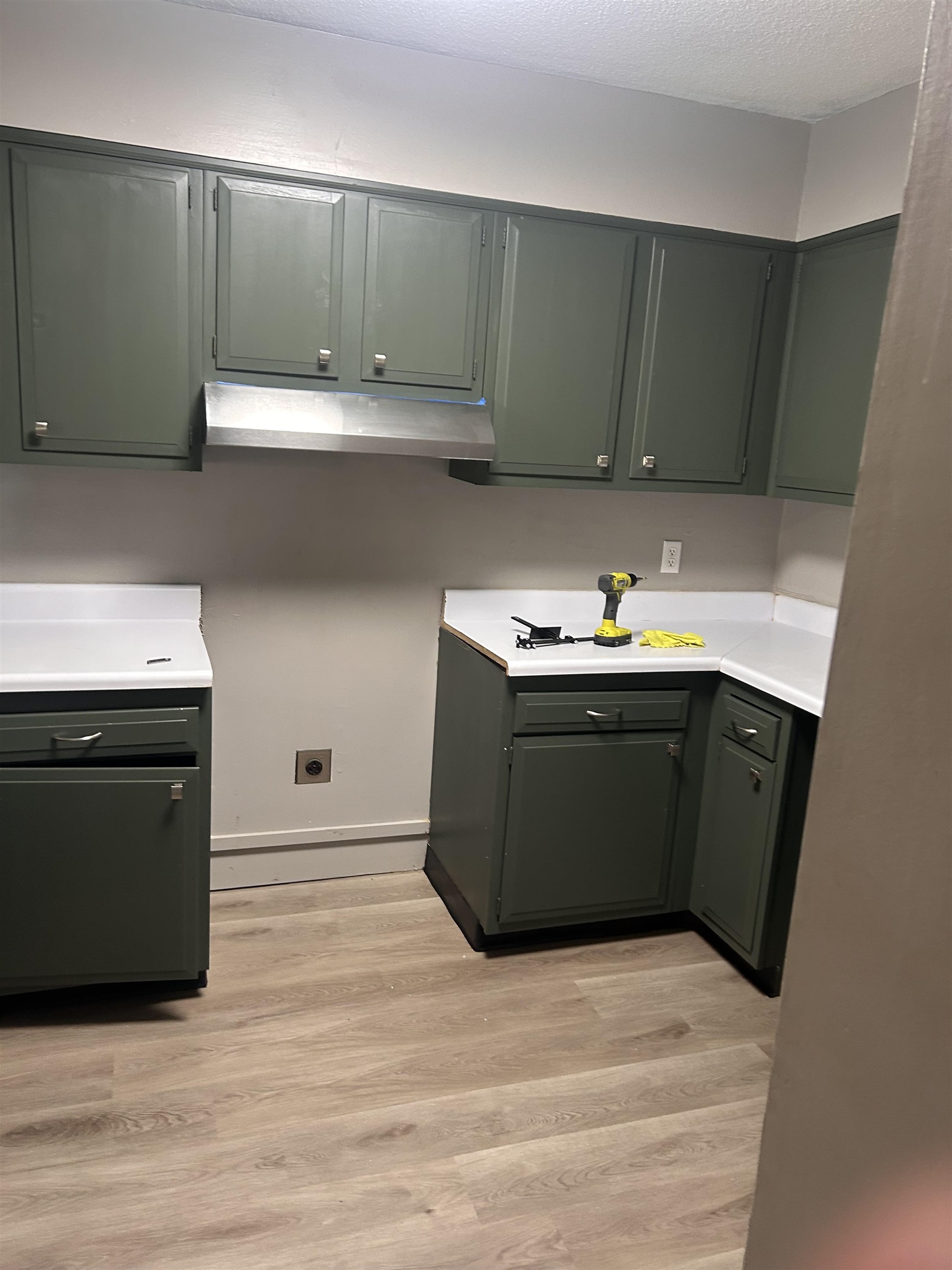 1772 6th Crompton Square, Unit B Memphis, TN 38134 - Photo 2 of 8 Kitchen featuring light countertops, light wood-style floors, under cabinet range hood, and a textured ceiling