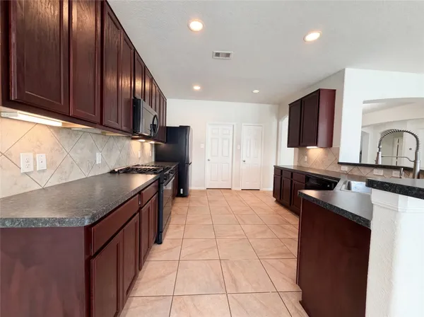 a kitchen with stainless steel appliances granite countertop a refrigerator and a stove top oven