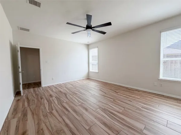 a view of empty room with wooden floor and fan