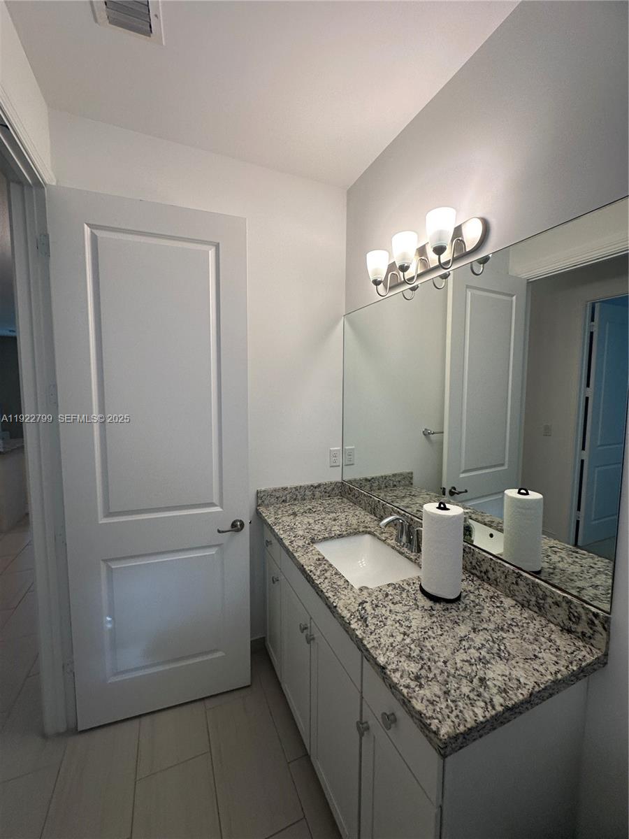 11718 Southwest 13th Ct. Pembroke Pines, FL 33025 - Photo 16 of 35 a bathroom with a granite countertop sink and a mirror