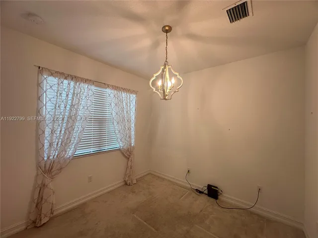 en empty room with a chandelier fan and a window