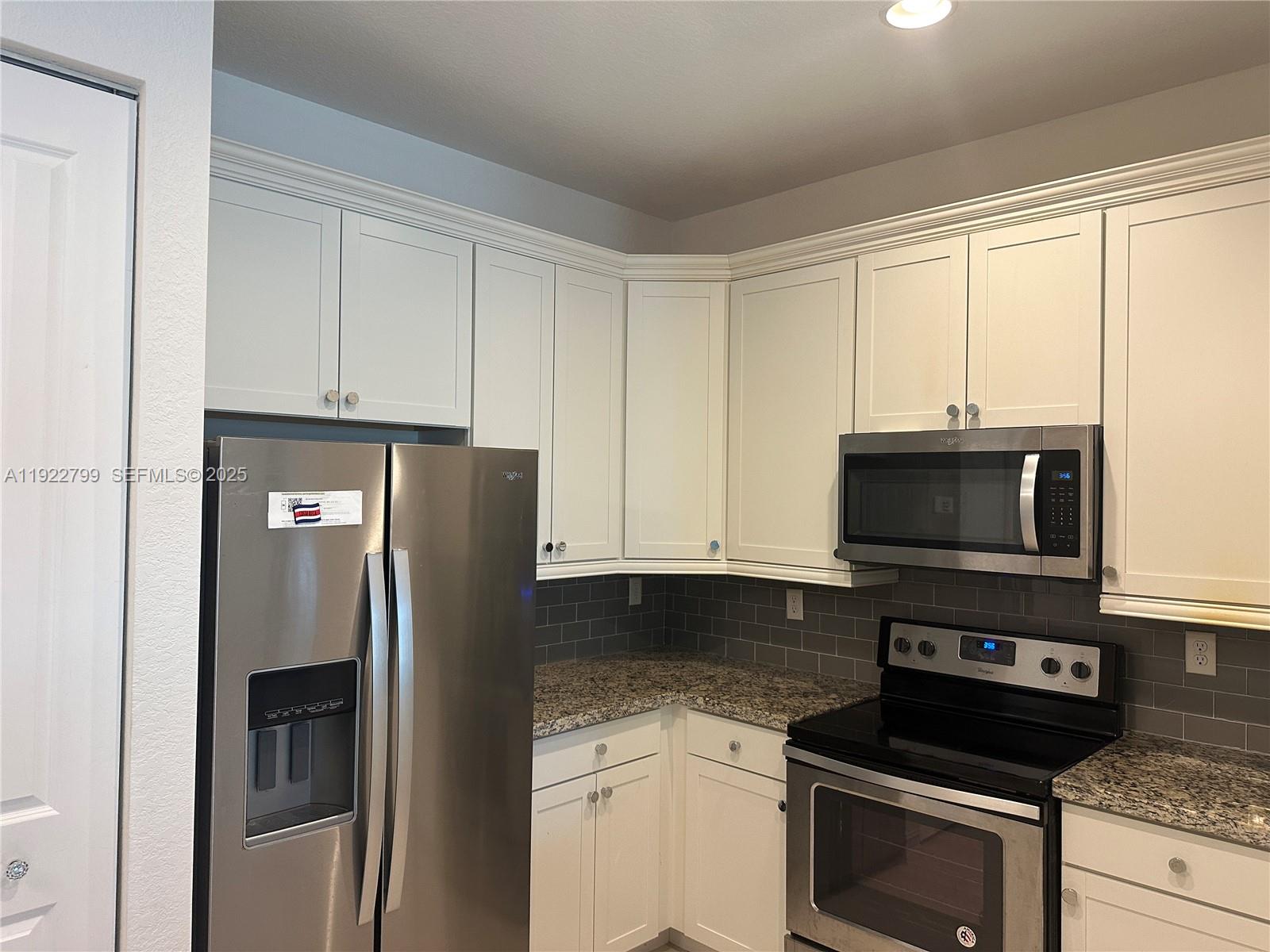 11718 Southwest 13th Ct. Pembroke Pines, FL 33025 - Photo 21 of 35 a kitchen with stainless steel appliances white cabinets a stove and a refrigerator