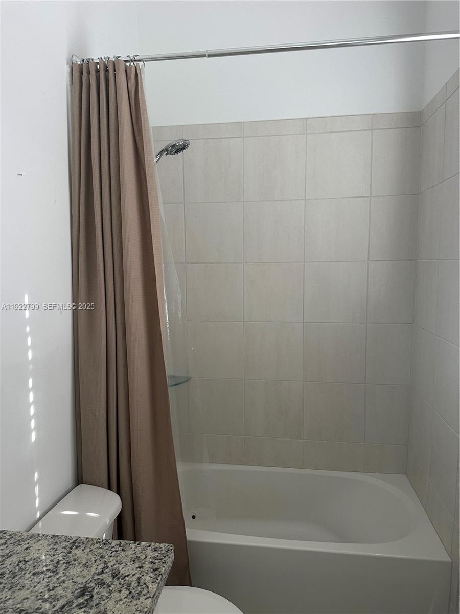 11718 Southwest 13th Ct. Pembroke Pines, FL 33025 - Photo 9 of 35 a bathroom with a shower curtain and a sink