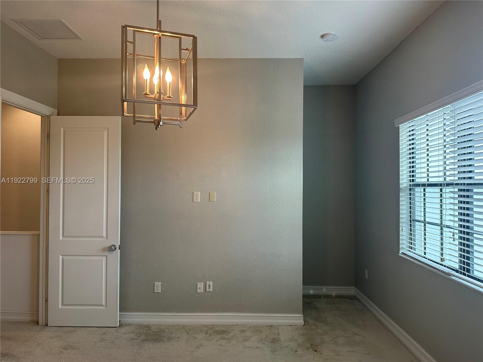 11718 Southwest 13th Ct. Pembroke Pines, FL 33025 - Photo 10 of 35 an empty room with chandelier fan and windows