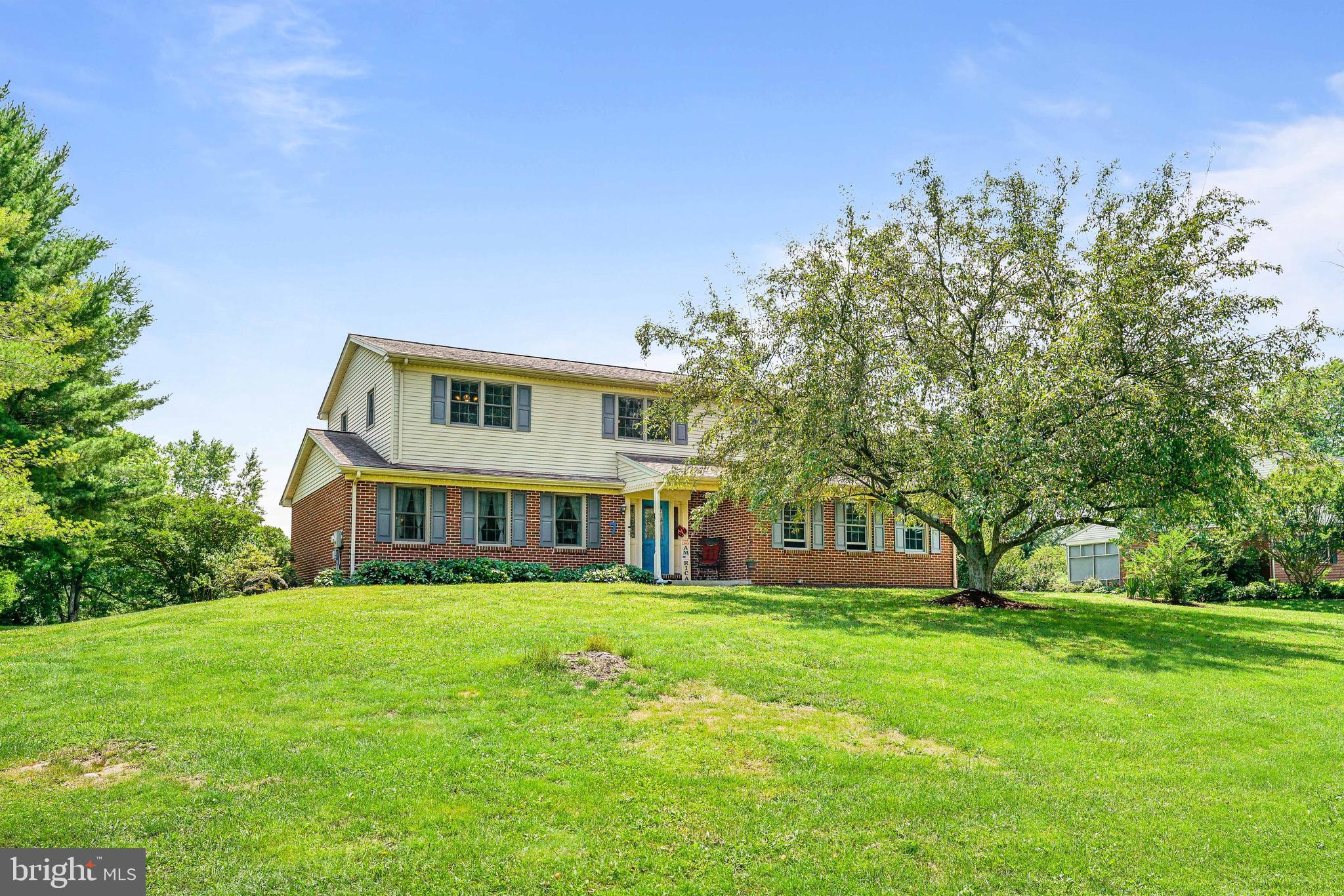 a view of house with a big yard and large trees