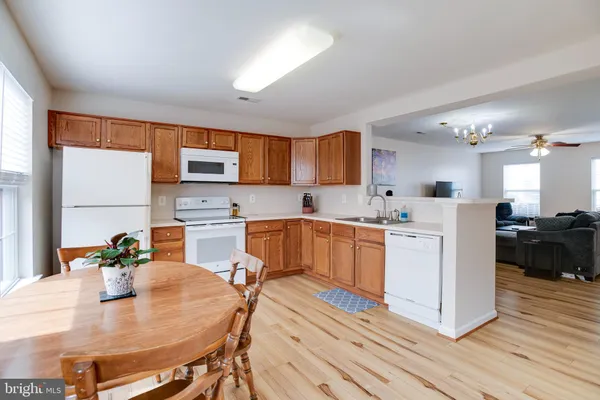 a open kitchen with stainless steel appliances granite countertop a stove a sink dishwasher and a refrigerator with wooden floor