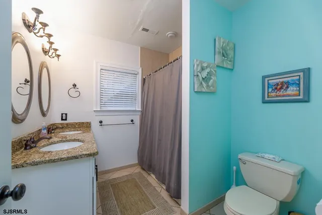 a bathroom with a granite countertop toilet a sink and a mirror