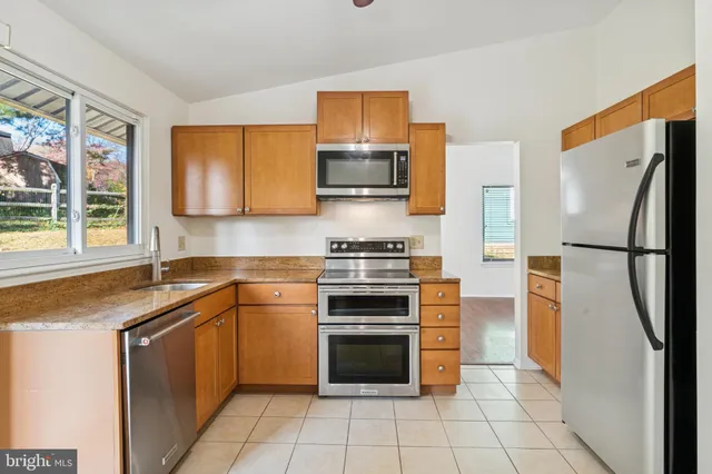 a kitchen with stainless steel appliances granite countertop a stove a refrigerator and a sink