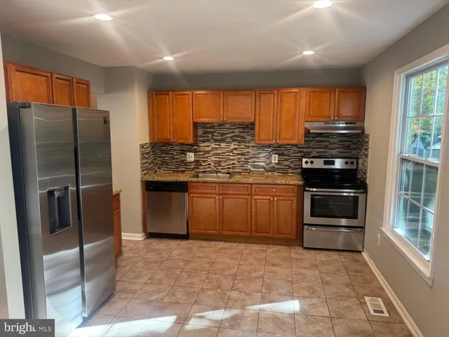 a kitchen with stainless steel appliances granite countertop a stove refrigerator and microwave