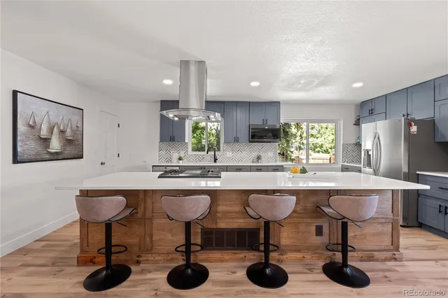 a kitchen with stainless steel appliances a table chairs refrigerator and sink