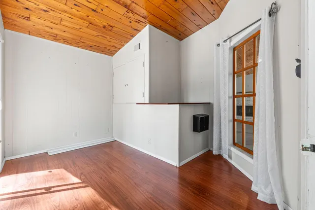 a view of a hallway with wooden floor and cabinet