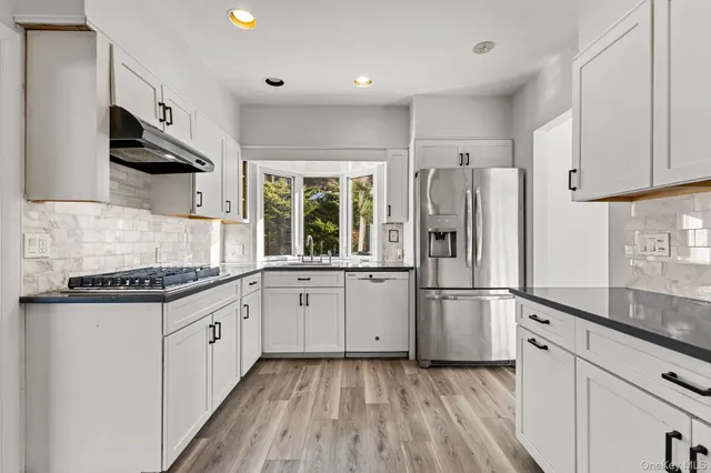 a kitchen with stainless steel appliances granite countertop a refrigerator and a stove top oven