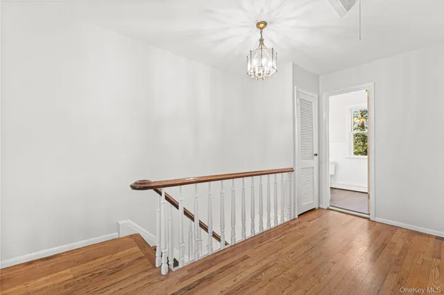 a view of a hallway with wooden floor and chandelier