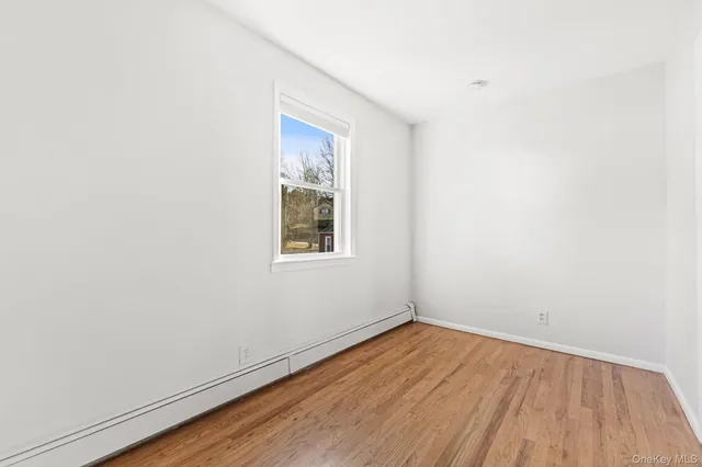 an empty room with a window and wooden floor