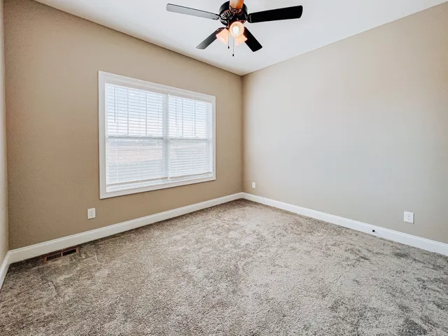 an empty room with a ceiling fan and window