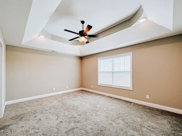 an empty room with windows and ceiling fan