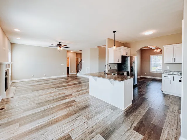 a large white kitchen with kitchen island a sink a center island and stainless steel appliances