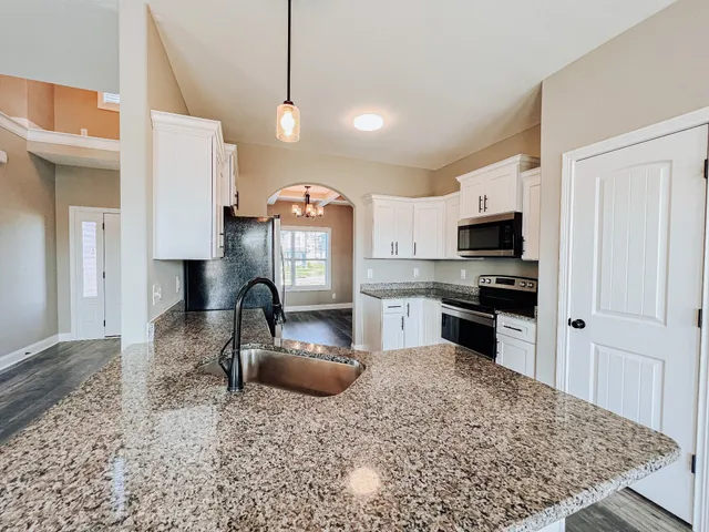 a kitchen with stainless steel appliances granite countertop a sink refrigerator stove and microwave