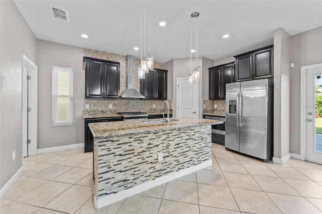 1040 Oliveto Verdi Court Brandon, FL 33511 - Photo 2 of 35 a kitchen with stainless steel appliances kitchen island granite countertop a refrigerator and a stove top oven
