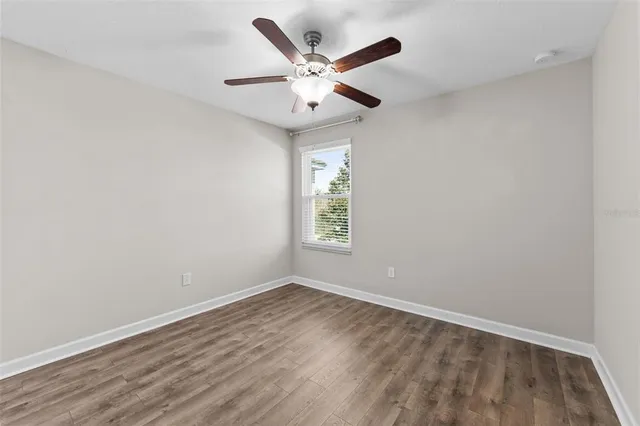 an empty room with a window and a ceiling fan