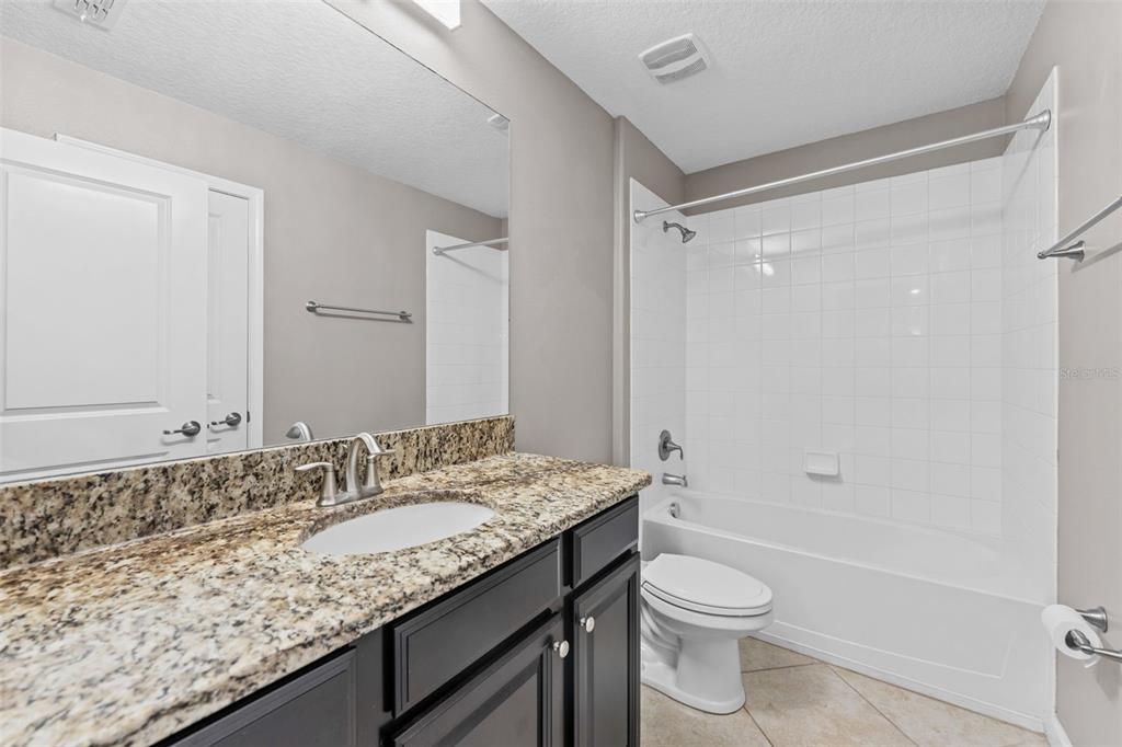 1040 Oliveto Verdi Court Brandon, FL 33511 - Photo 23 of 35 a bathroom with a granite countertop sink toilet and shower