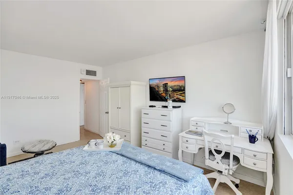 a bedroom with a bed and a flat tv screen on dresser